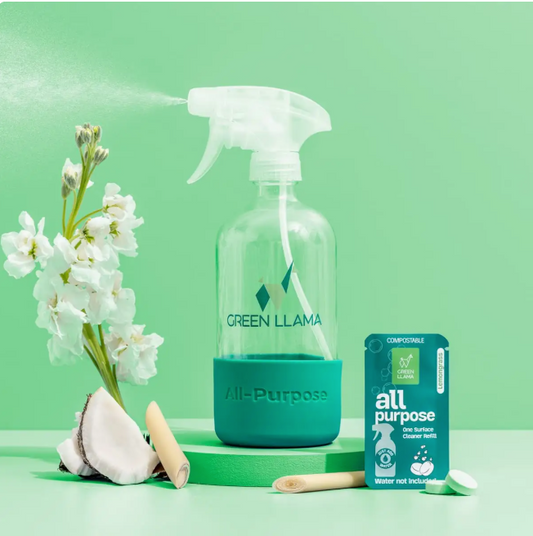 Green Llama all-purpose cleaner bottle with packaging and flowers on a green background