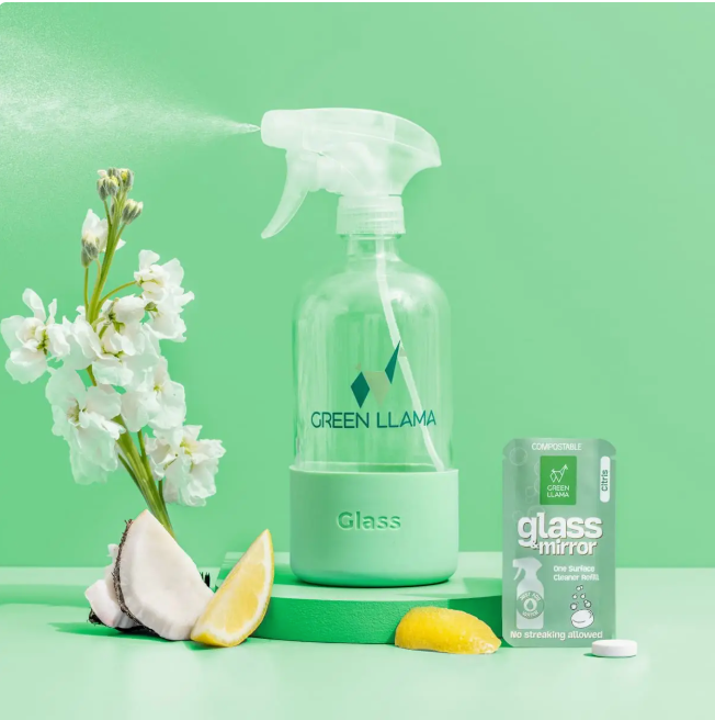 Green Llama glass cleaner bottle with flowers and lemon on a green background